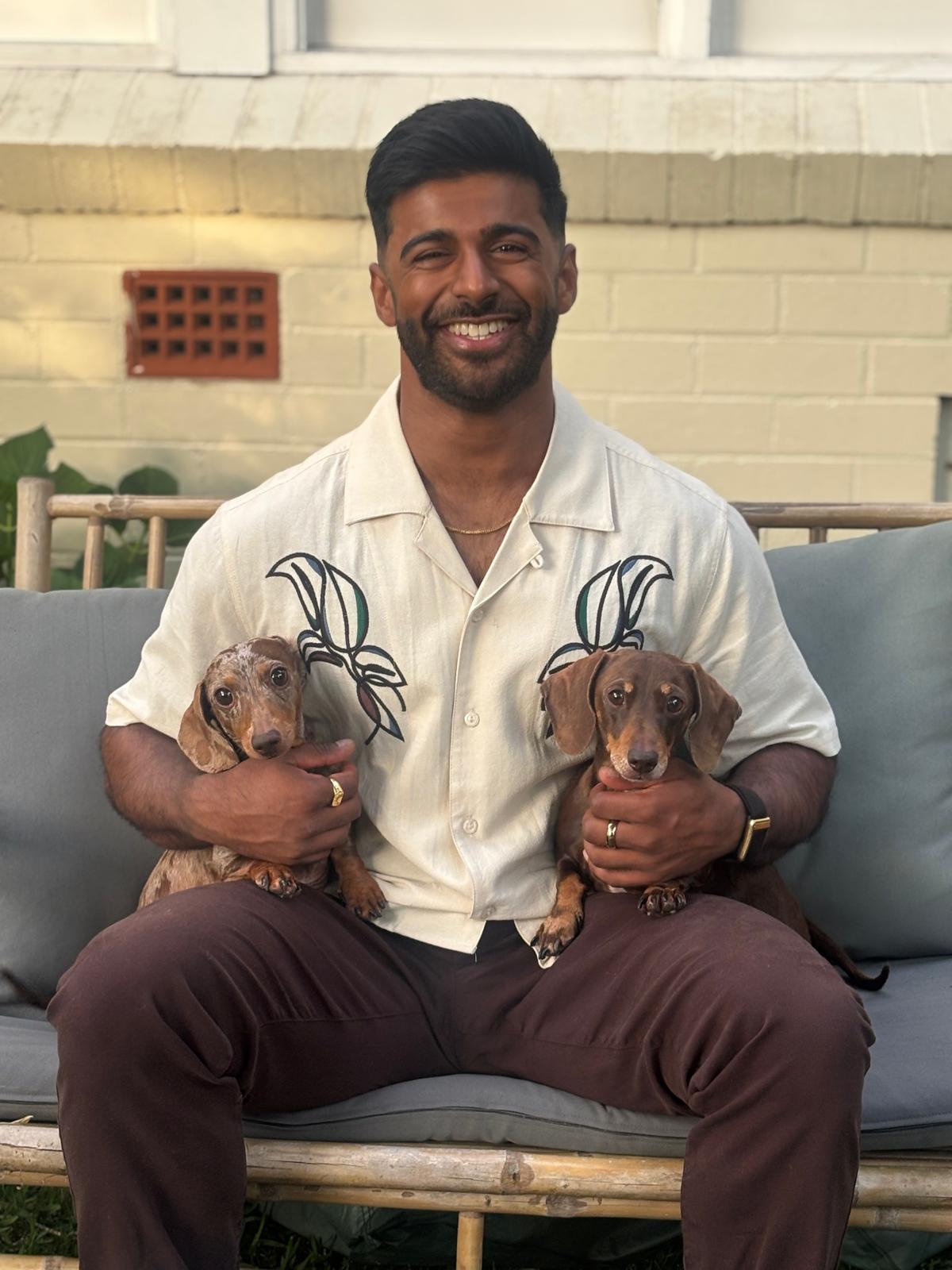 Dr Patel on a bamboo bench with his two dachshunds, Bambi and Tinkerbell.