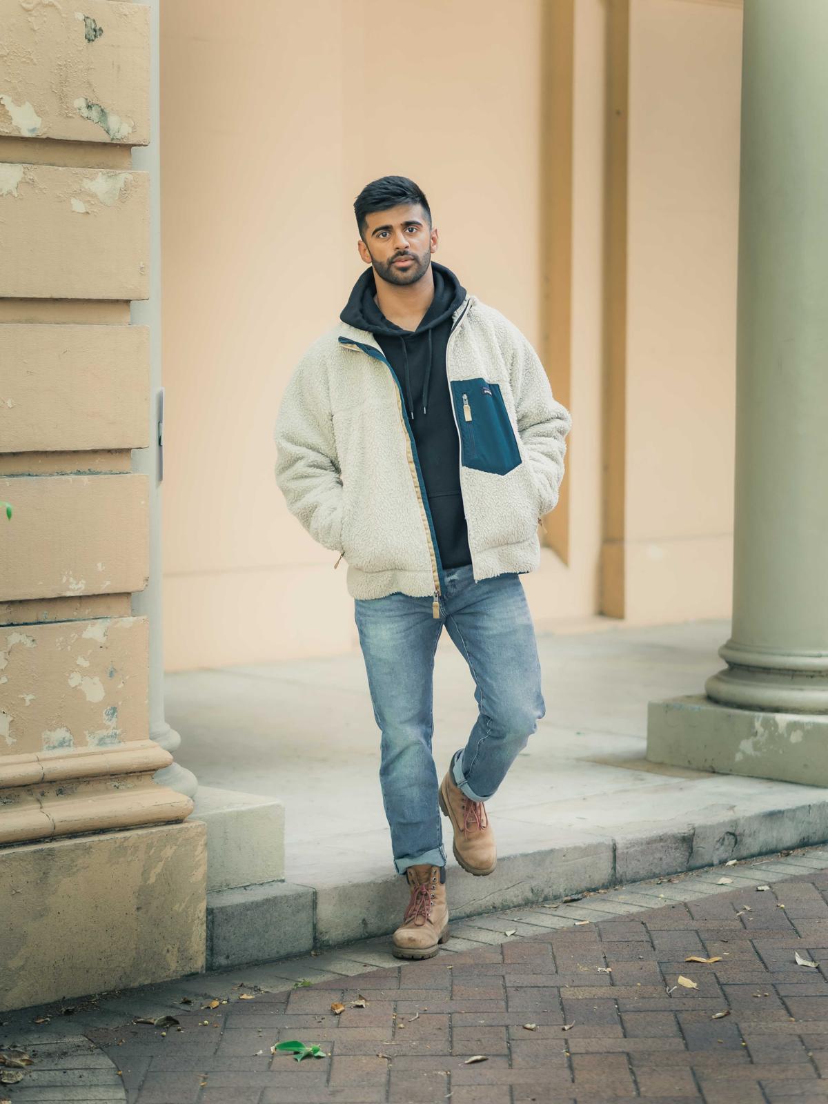 Dr Vinay Patel, standing in a cream fleece against a terracotta wall in Sydney.